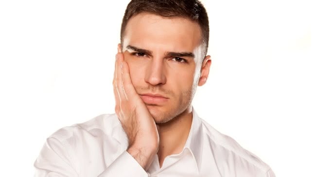 Man holding cheek with tooth pain
